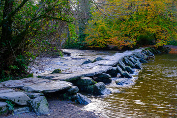 Signs of autumn at Tarr Steps clapper bridge after rain in Exmoor National Park, Somerset, UK