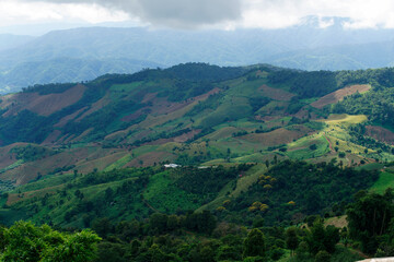 Naklejka premium Lush Green Mountain Landscape with Rolling Hills and Cloudy Sky