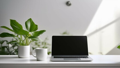 Fototapeta premium minimalist workspace with green plant laptop and white cup conveying a clean and modern aesthetic