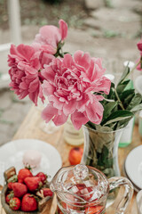 Close up view of fresh pink summer flowers in a vase on a wooden table outdoors