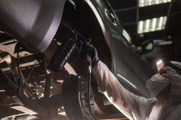 The master sprays an anti-corrosion compound on the bottom of the car. 