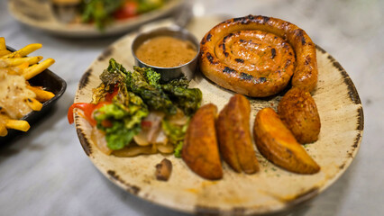 mouthwatering German worst curled up cumberland sausage meal featuring a grilled sausage, loaded cheese fries, and fresh vegetables served on a rustic plate