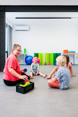 Kids physical therapy. Group of children and female therapist exercising during session. Bilateral...
