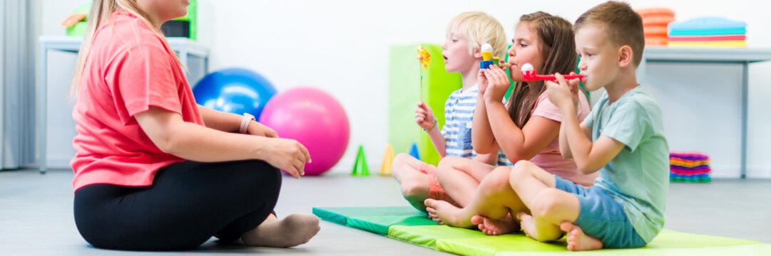 Group of young children making breathing exercises during physical therapy session. Kids in group physiotherapy.
