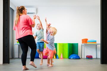 Young children exercising with physical therapist during group therapy session. Child occupational...