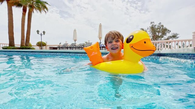 Child happily jump into bright blue pool in inflatable duckling
