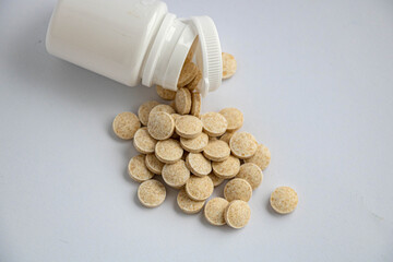 Herbal pills from a jar on a white background, upper view close-up shot