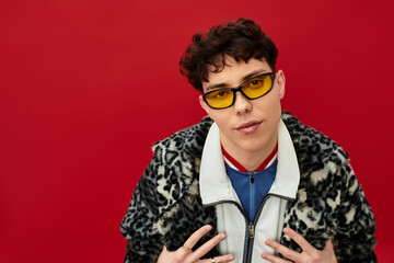 Obraz premium Handsome man showcases unique style with yellow glasses and animal print coat in a bold setting.