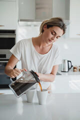 Woman Pouring Coffee from French Press in Modern Kitchen