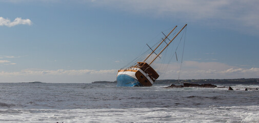 Captivating image of a shipwreck leaning on rocks in a rough sea during sunset, creating a dramatic scene of maritime disaster and the power of nature