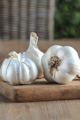 Three fresh organic garlic bulbs on wooden cutting board. Close up. 