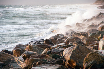 The ocean is rough and the waves are crashing against the rocks