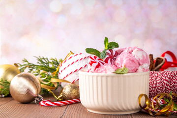 Festive Christmas holiday sweet mint candy cane peppermint ice cream in ceramic bowl, frozen creamy red and white yogurt sorbet, on Christmas New Year decorated background, copy space