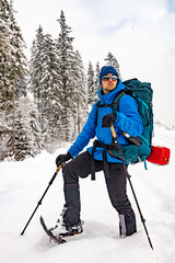 A guy walks in snowshoes with a backpack in the snow, winter hiking.