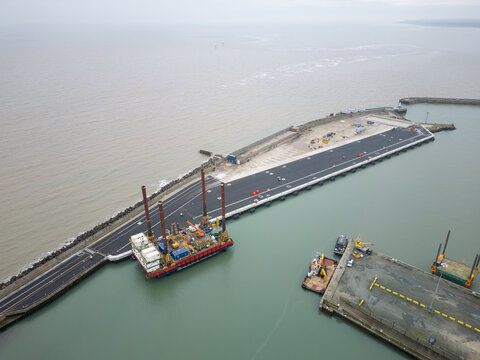 Aerial view of the commercial port of Lowestoft on the Suffolk, UK coastline. A large, stilted barge is seen in wet dock together with an empty jetty for smaller vessels.