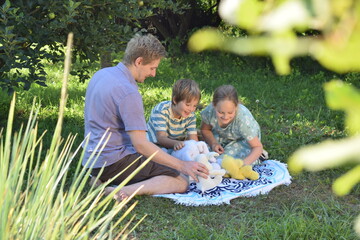 A young father spends quality time with his children outdoors in the backyard, engaging in a playful tea party with stuffed animals. The scene highlights family bonding, imagination, and joy.