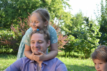 A young father spends quality time with his children outdoors in the backyard, engaging in a playful tea party with stuffed animals. The scene highlights family bonding, imagination, and joy.