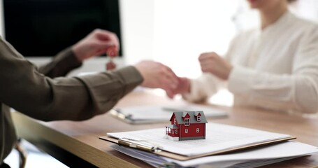 A skilled real estate agent hands over the keys for a successful property deal to the excited new owner