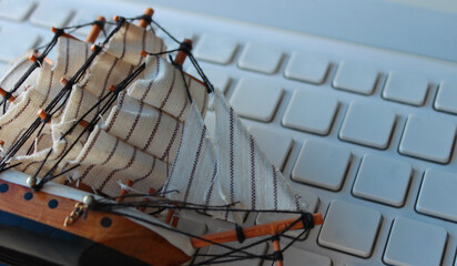 Toy Model Of Sailing Ship Lies On Blank Computer Keypad  
