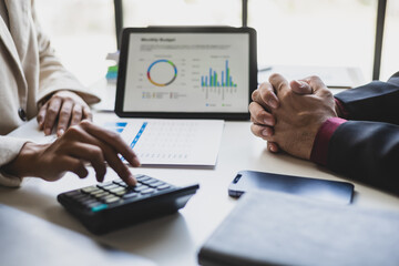 Meeting with a financial advisor and auditor are analyzing the financial figures in the business report. Investors are discussing cost analysis and reducing costs to increase profitability.
