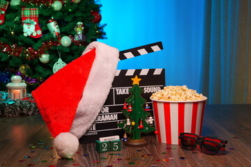 Merry Christmas and New Year Holidays Scene. Santa Claus Hat, Movie Clapperboard, Christmas Tree, Garland, Neon Lights, Cinema Popcorn, and 3D Glasses. Perfect Setting for Holiday Movie Nights at Home