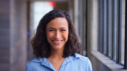 Head And Shoulders Portrait Of Confident Businesswoman Standing By Window In Modern Office