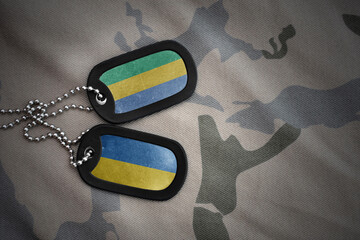 army blank, dog tag with national flag of gabon and ukraine on the khaki texture background....
