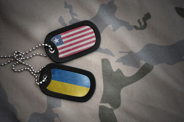 army blank, dog tag with national flag of liberia and ukraine on the khaki texture background....