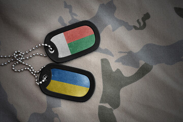 army blank, dog tag with national flag of madagascar and ukraine on the khaki texture background....