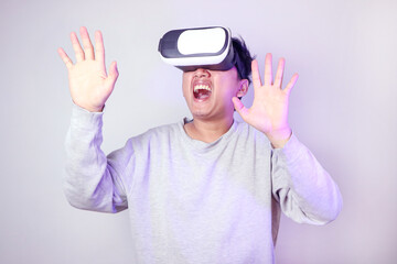 Naklejka premium Portrait of scared man in shirt and vr headset, playing virtual reality game with shocked face, keeps mouth widely. Indoor studio shot isolated on colorful neon light background.