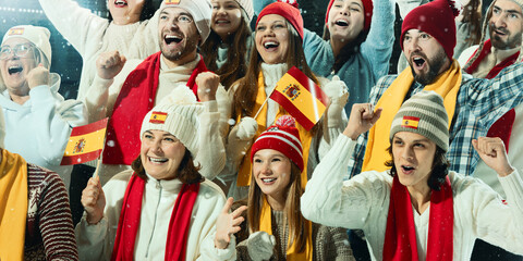 Close-up of young sports fans, men and women, in red and white attire, enthusiastically supported the Spanish team in lively stadium environment. Concept of sport, game, competition, emotions