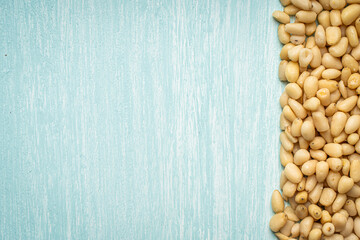 Pine nuts on blue, wooden background. Space for text. Copyspace.