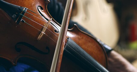 Super slow motion macro of master luthiers hands draw bow across strings of handmade violin at 1000 fps. Each movement showcase precision and artistry in both playing and craftsmanship of instrument