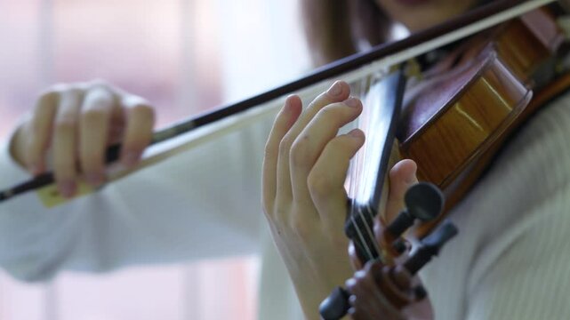 Fiddler hand swiftly move bow across violin strings, playing fast. Female musician focus on string technique, fast tempo, musical practice, concert, orchestral rehearsal, refined performance. Close up
