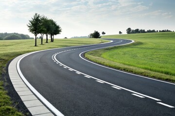 A winding asphalt road curves through a vibrant green field under a partly cloudy sky