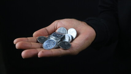 Close up of male hands holding Indonesian coins, savings and banking concept