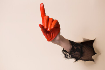 A woman's hand in a leather orange glove is pointing with her index finger