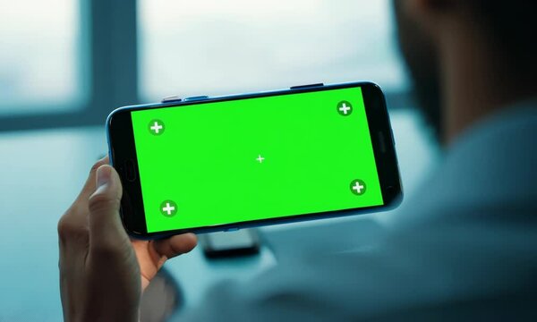 Smartphone user looking green screen display at office desk close up