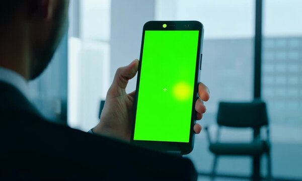 Smartphone user looking green screen display at office desk close up