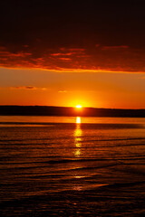 sunset over a body of water with a mountain