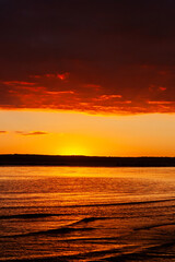 sunset over a body of water with a mountain