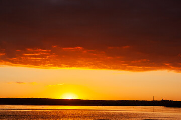 Fototapeta premium sunset over a body of water with a mountain