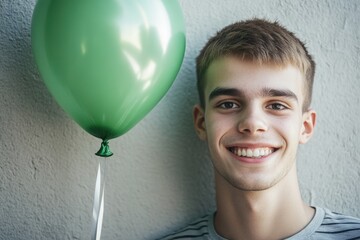 A happy young man holds a bright green balloon, perfect for a birthday party or celebration