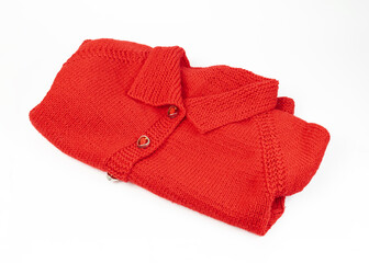 A red knitted jacket lies on a white background