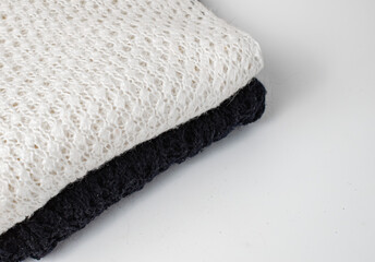 A black and white knitted product are stacked on a white background
