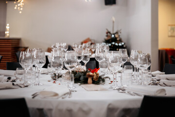 Elegant holiday table setup with crystal-clear glassware, festive centerpiece, and white tablecloth, perfect for a formal dinner or celebration