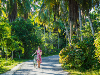 Cute woman and vintage bicycle against palm trees background. Beautiful views and sights of...
