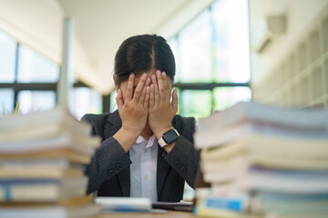 Female office worker, independent businesswoman feeling stressed, achy, and sleepy while working on a laptop. Tired Asian businesswoman at the office Office syndrome concept.