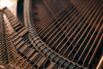 Top view detail shot of intricate piano strings inside classic grand piano in warm natural light, copy space