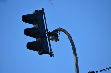 A traffic light is lit up with a blue sky in the background. The light is on the top of a pole.